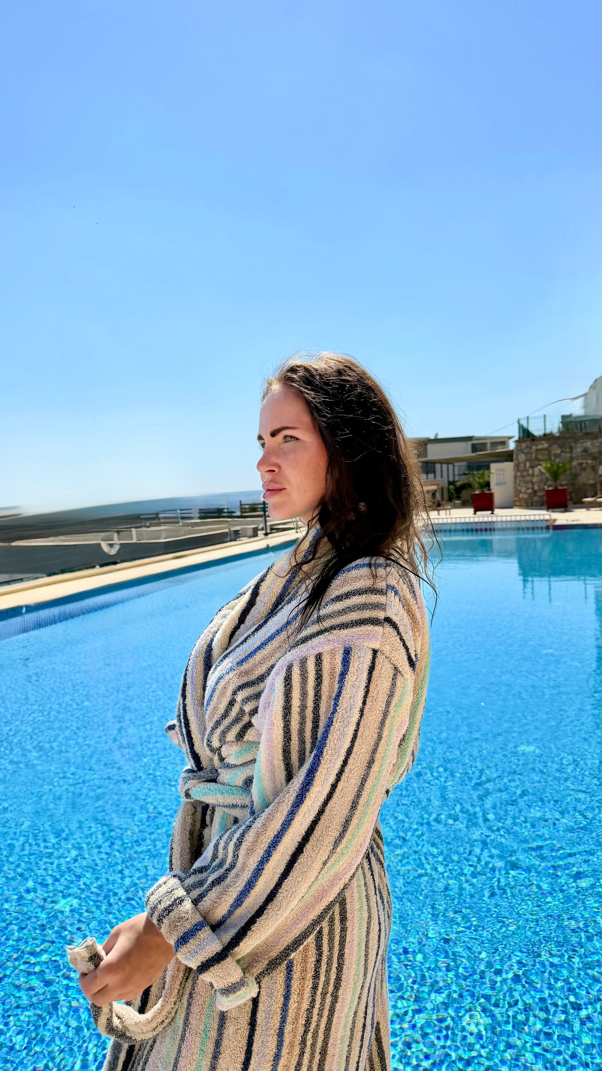 Kvinde i stribet morgenkåbe ved poolen